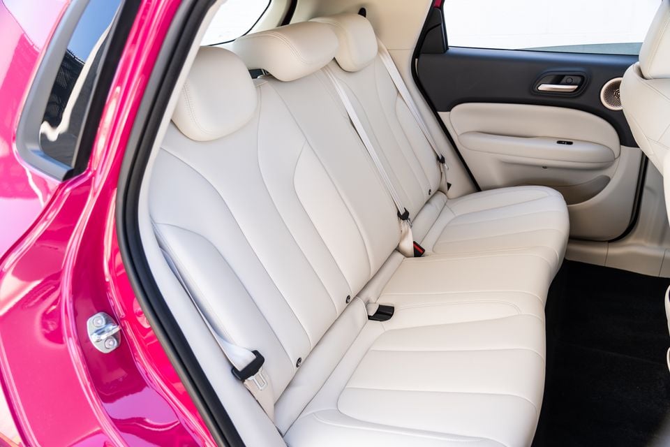Cream leather rear bench seat of the GWM Ora 5, seen through the open rear door of the pink body