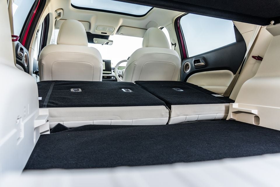 Boot of the GWM Ora 5 with the rear seats folded flat, showing the extended cargo floor and cream leather front seats beyond