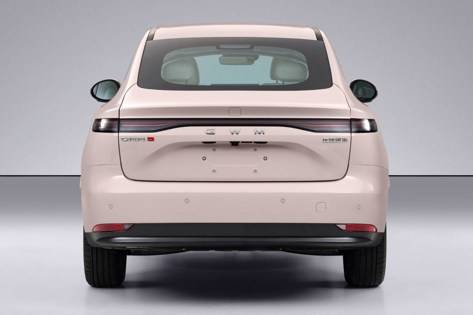 Rear view of a GWM ORA 5 sedan in a light pink colour, shown in a studio setting