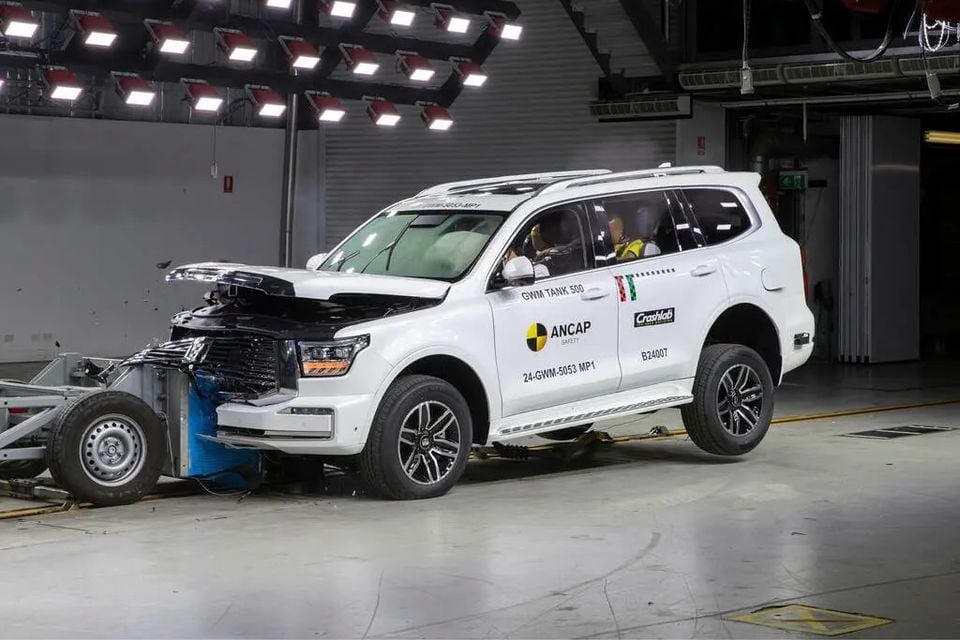 A white GWM Tank 500 SUV with a crumpled front end undergoes an ANCAP frontal crash test in a testing facility