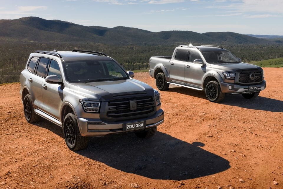 A GWM Tank 500 SUV and GWM Cannon Alpha ute parked on red dirt with mountain ranges in the background