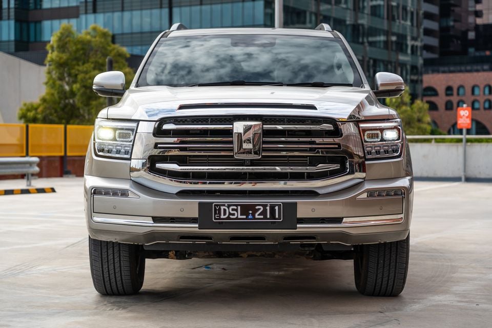 A GWM Tank 500 Hi4-T PHEV large SUV seen from the front, finished in a champagne/silver colour, photographed in an urban setting with a Victorian number plate