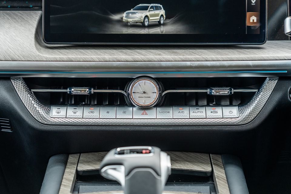 Interior centre console of the GWM Tank 500 Hi4-T PHEV showing the analogue clock, climate control buttons, air vents, touchscreen infotainment display, and gear selector