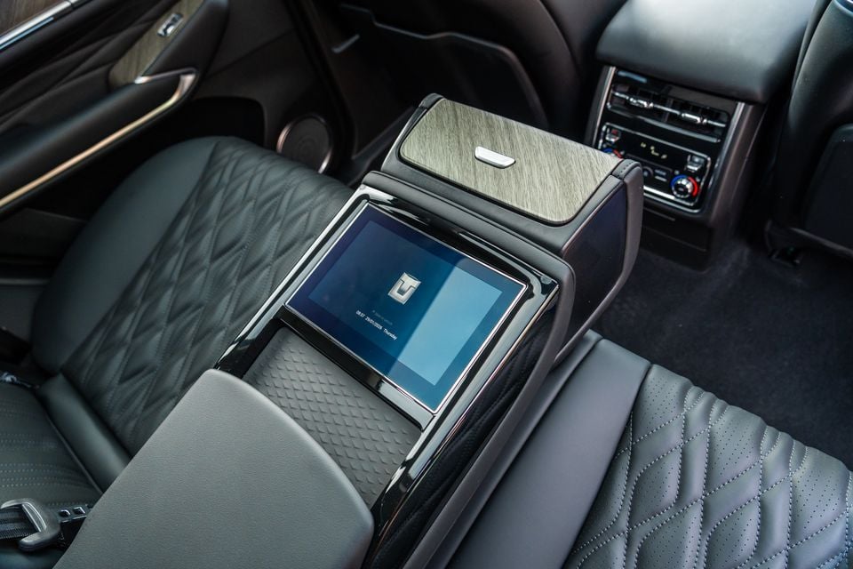 Rear centre console of a GWM Tank 500 Hi4-T PHEV showing a touchscreen display, wood-grain trim, quilted leather seats and rear climate controls
