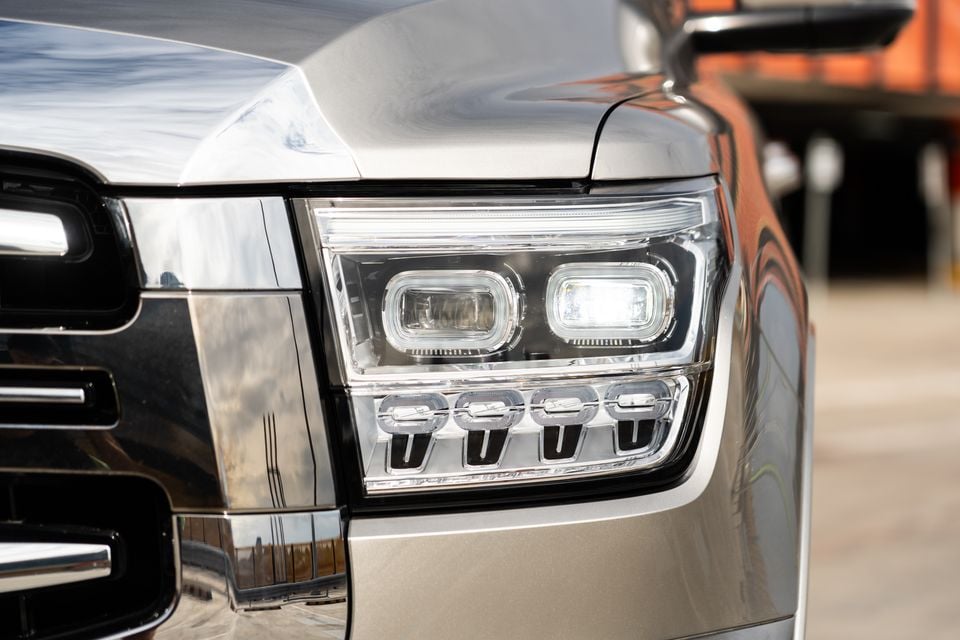 Close-up of the LED headlight on a GWM Tank 500 PHEV, showing dual rectangular projector lenses and four lower LED daytime running lights on a silver-grey body