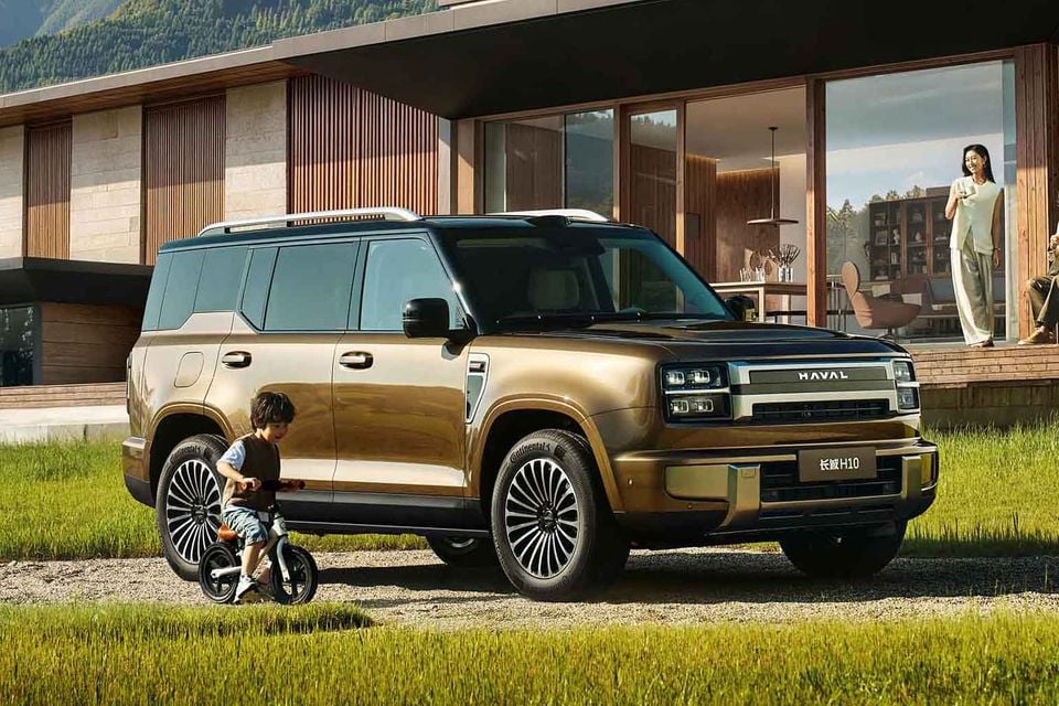 A gold Haval H10 large SUV parked outside a modern home, seen from the front-side angle