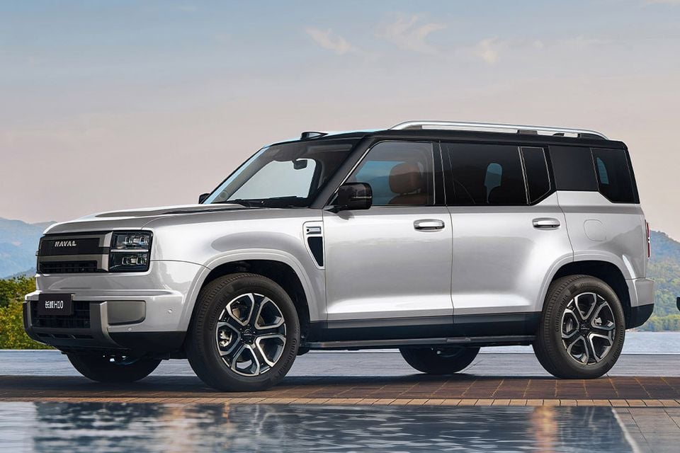 A silver Haval H10 five-seat SUV seen from the front-side angle, parked near a waterfront with mountains in the background.