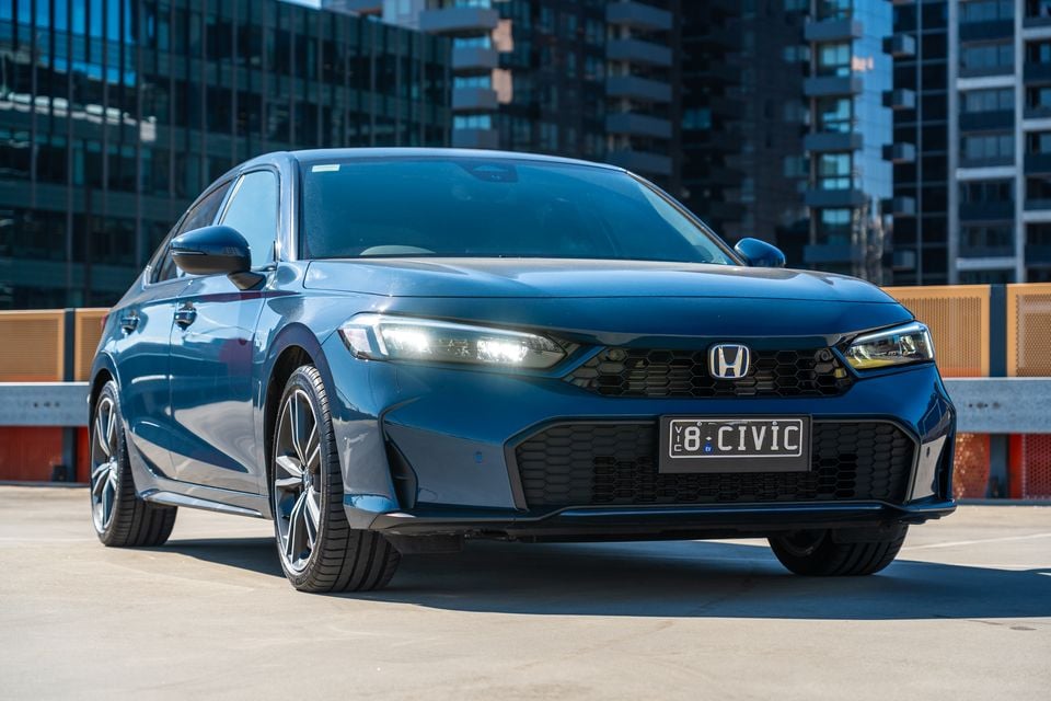 A blue Honda Civic sedan seen from the front at a low angle on a rooftop car park in an urban setting