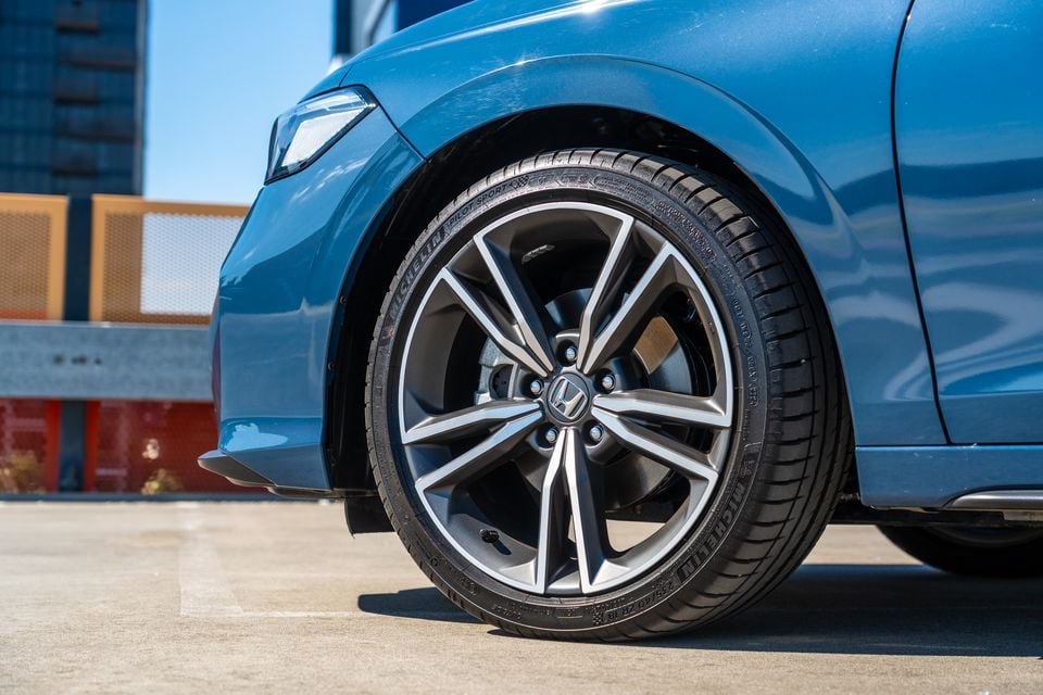 Close-up of a Honda alloy wheel with Michelin Pilot Sport tyre on a blue Honda Civic e:HEV, seen from the front side