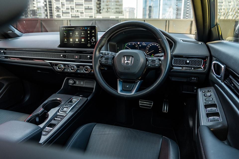 Honda Civic e:HEV interior showing the steering wheel, touchscreen infotainment system, instrument cluster, centre console and dashboard