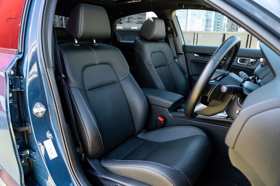 Black leather front seats of a Honda Civic e:HEV interior, viewed through the open driver's door with the steering wheel visible on the right