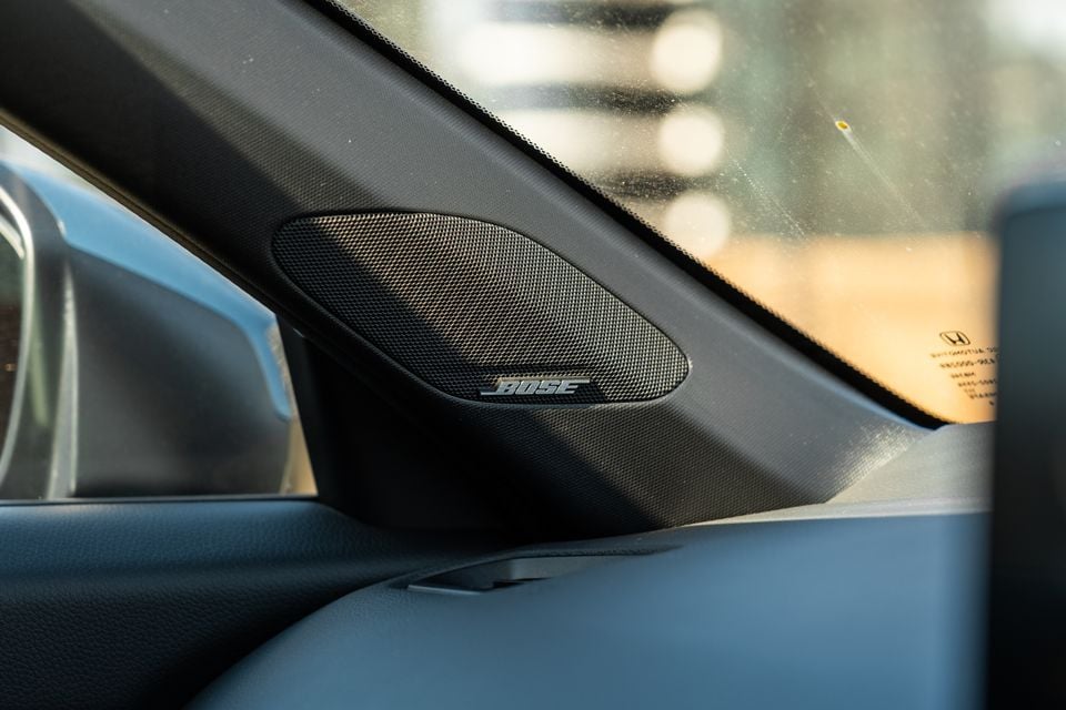 A Bose speaker mounted on the dashboard corner of a Honda Civic, near the windscreen