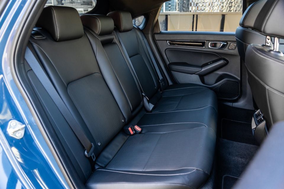The rear seat interior of a Honda Civic e:HEV, showing black leather seats, seatbelts, door trim, and speaker grille