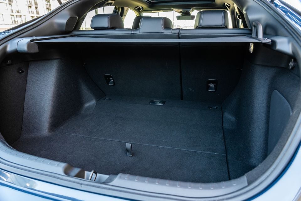The empty boot of a Honda Civic e:HEV, showing a flat carpeted load floor with fold-down rear seat latches and a privacy blind above