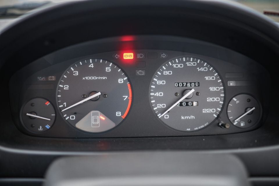 Close-up of a car instrument cluster showing a tachometer, speedometer reading approximately 20 km/h, odometer at 7,600 km, and a fuel gauge near full