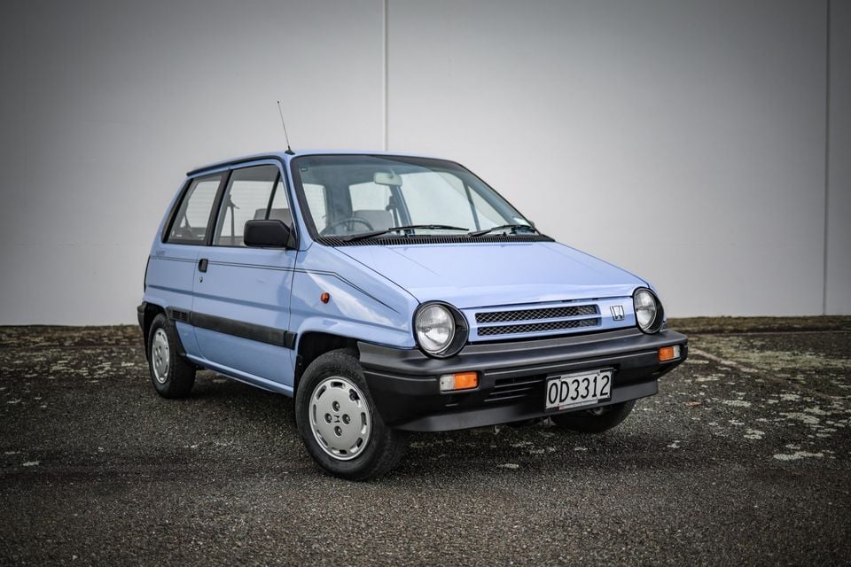 A light blue Honda City hatchback parked outdoors, seen from the front three-quarter angle