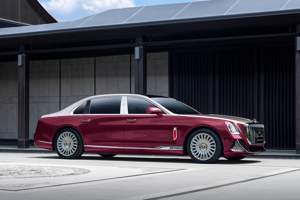 A maroon and champagne Hongqi Guoya luxury sedan parked side-on outside a modern building