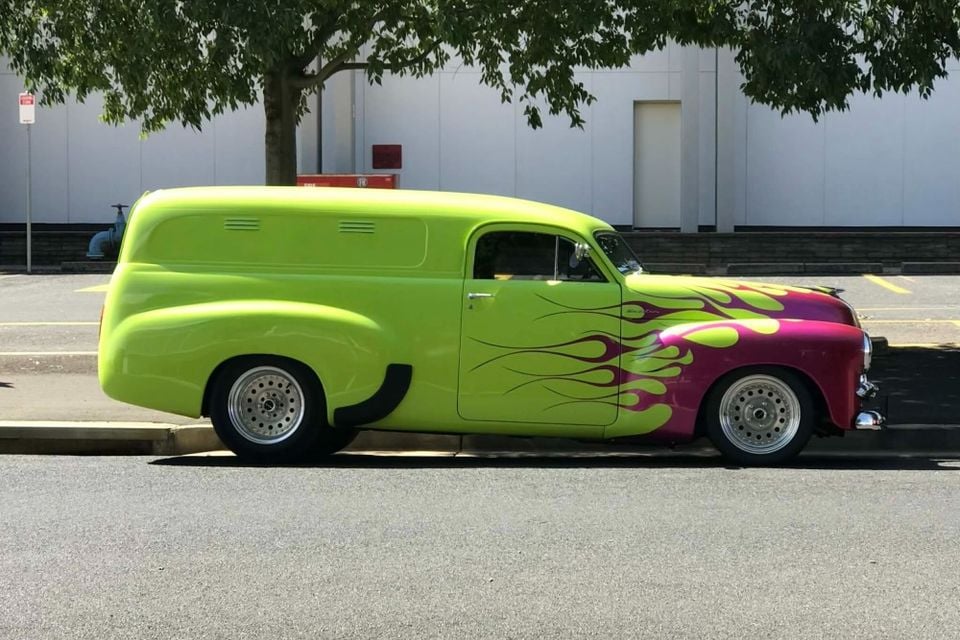 A heavily customised vintage panel van painted in lime green with pink and green flame graphics, parked on a street at the Hot Wheels Legends Australia 2026 event