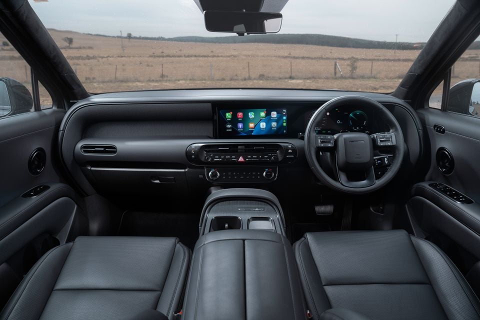 Interior view of a Hyundai Palisade showing the dashboard, widescreen infotainment display with Apple CarPlay, steering wheel, and dark leather front seats