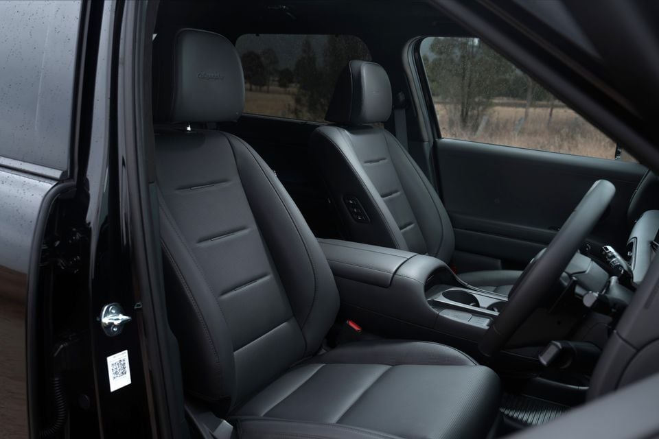 Interior view of a Hyundai Palisade Calligraphy showing the front seats, centre console, and steering wheel with dark leather upholstery, photographed through the open driver's door.