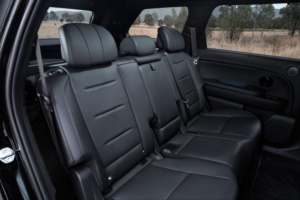 Black leather second-row seats inside a Hyundai Palisade SUV, with a third row visible to the right