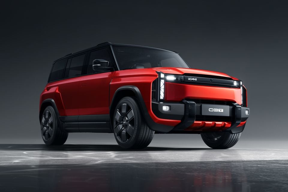 A red iCar 03T SUV photographed from the front-side angle in a studio setting