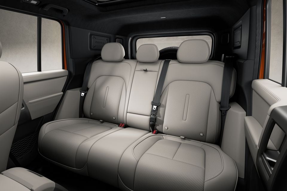Leather-trimmed rear seats with three headrests and seatbelts inside an SUV interior