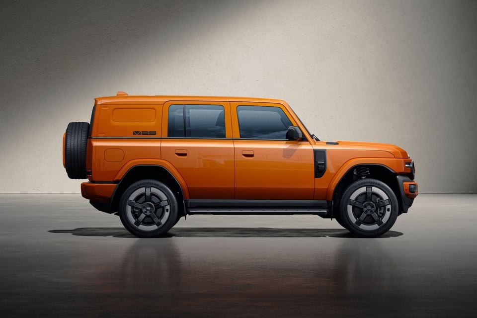 An orange ICAUR V25 four-door SUV shown from the side in a studio setting, with a rear-mounted spare wheel and black alloy wheels