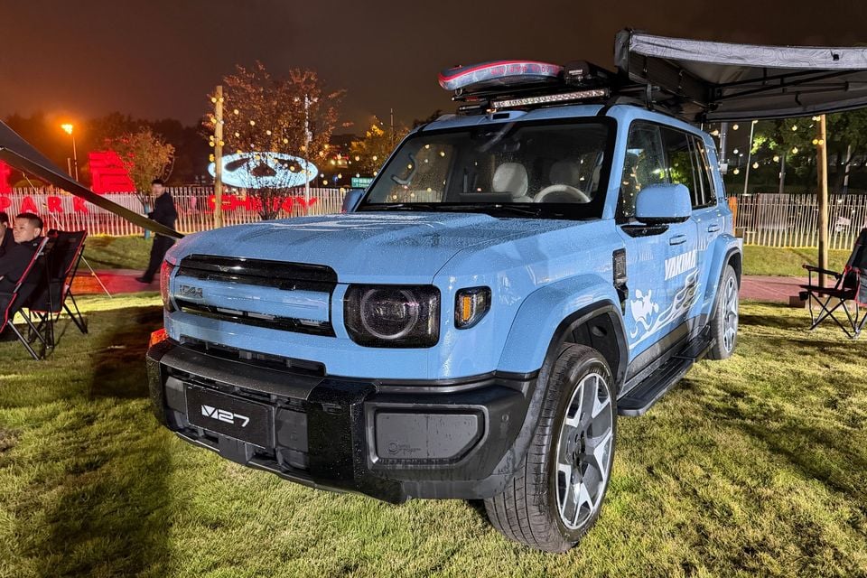 Blue iCaur V27 with roof-mounted accessories and a side awning at an outdoor display in China