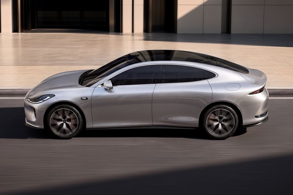 A silver IM L6 sedan seen from the side while driving past a building