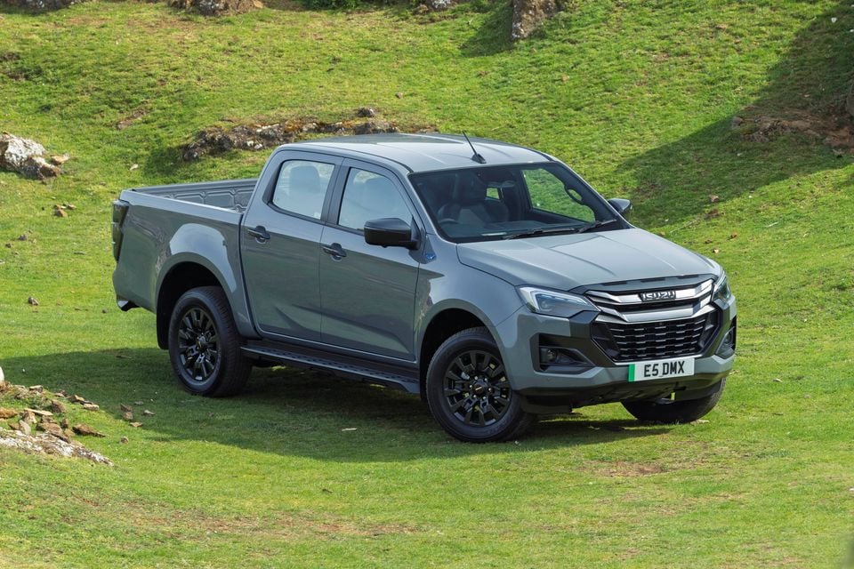 A grey Isuzu D-Max dual-cab ute parked on a grassy hillside, seen from the front quarter