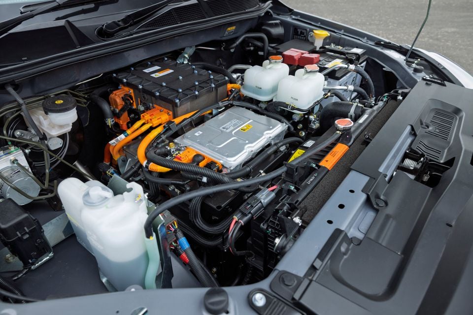 The electric motor and high-voltage components under the bonnet of an Isuzu D-Max EV are visible with orange high-voltage cabling.