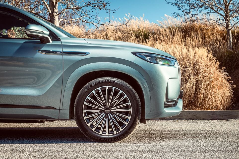 Close-up of the front wheel and fender of a light green Jaecoo J8 PHEV SUV, showing a multi-spoke alloy wheel with Michelin tyres