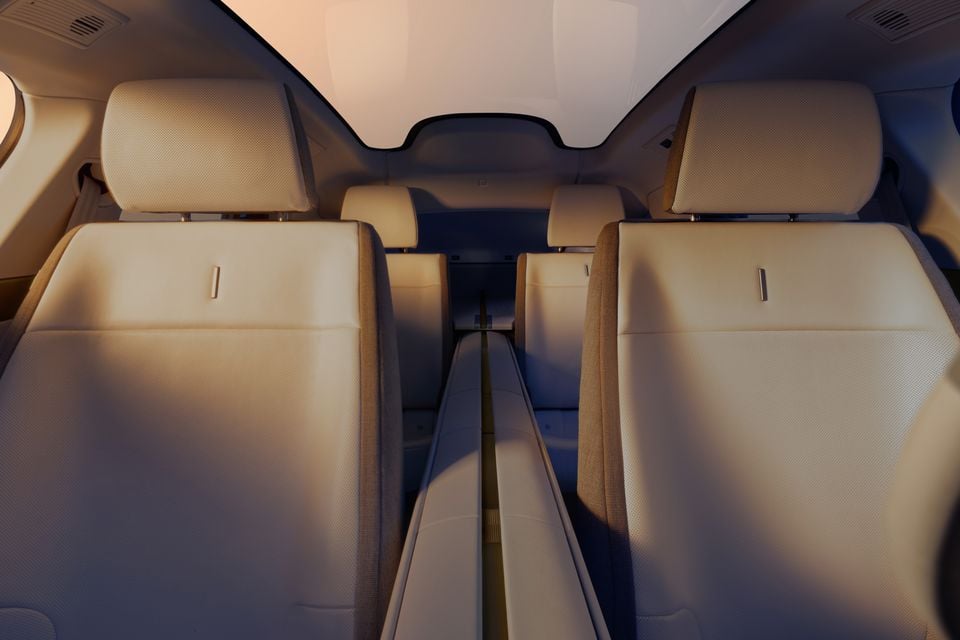 Interior view of a Jaguar Type 00 showing cream leather rear and third-row seats with a panoramic glass roof overhead