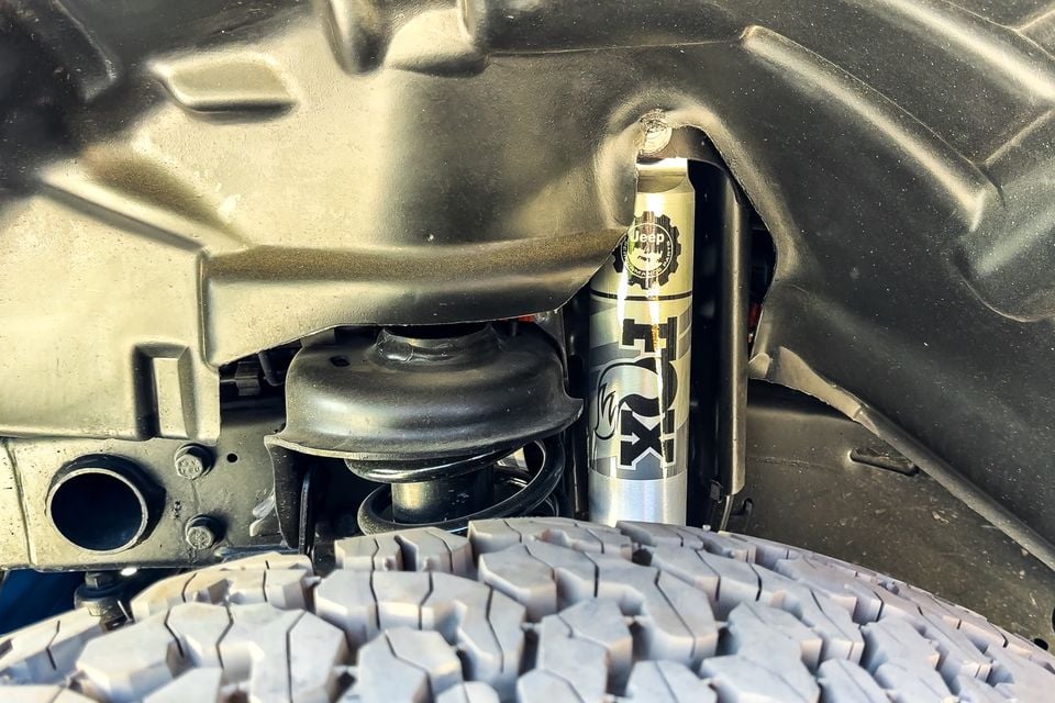 Fox shock absorber with Jeep Performance Parts branding and coil spring inside the wheel well of a Jeep Wrangler 392, above an all-terrain tyre