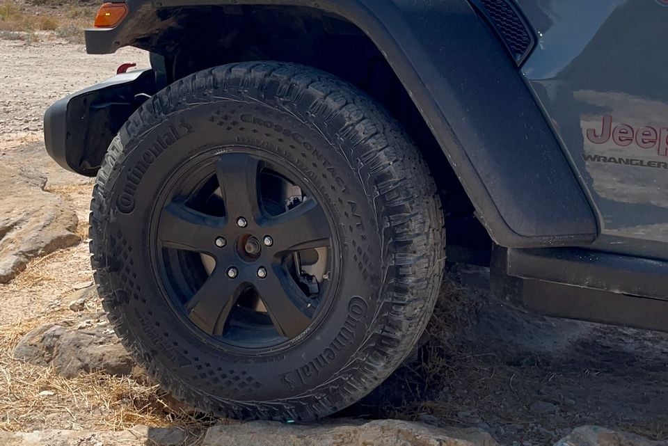 Close-up of a Continental CrossContact AT2 tyre and black alloy wheel on a Jeep Wrangler on rocky terrain