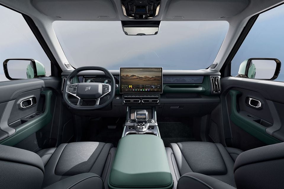 Dashboard and front cabin of the Jetour T1 with a large central touchscreen, steering wheel, dark leather seats and green accents