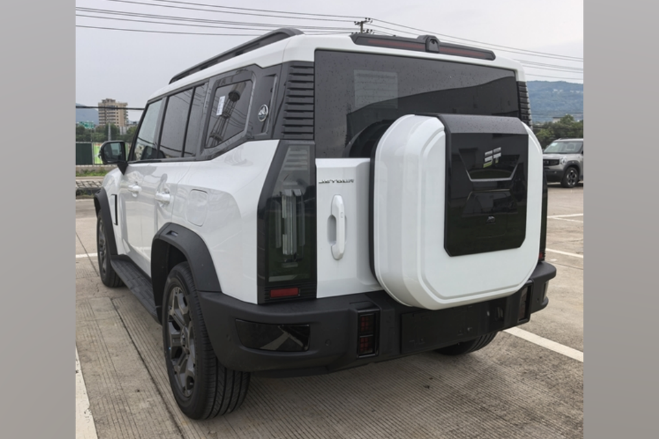 A white Jetour T2 SUV parked in a car park, seen from the rear quarter with its covered tailgate-mounted spare wheel