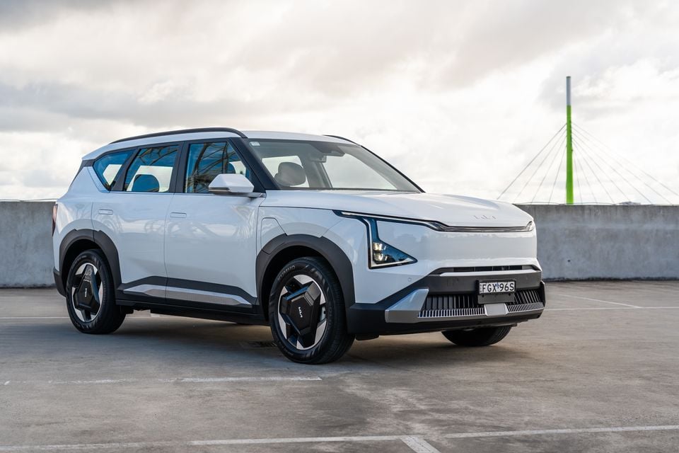 A white Kia EV5 SUV seen from the front-left angle in a rooftop car park