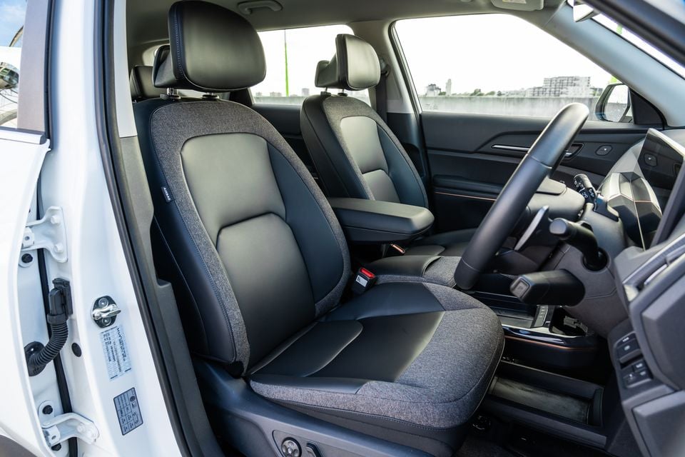 Interior view of a Kia EV5 showing the front seats with two-tone fabric and leather upholstery, centre console, and steering wheel