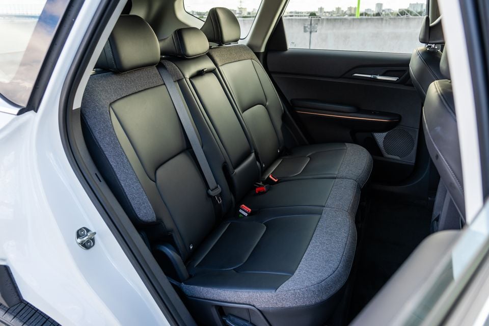 Rear passenger seats of the Kia EV5 Air Long Range, showing black leather and fabric upholstery with seatbelts and a door-mounted speaker