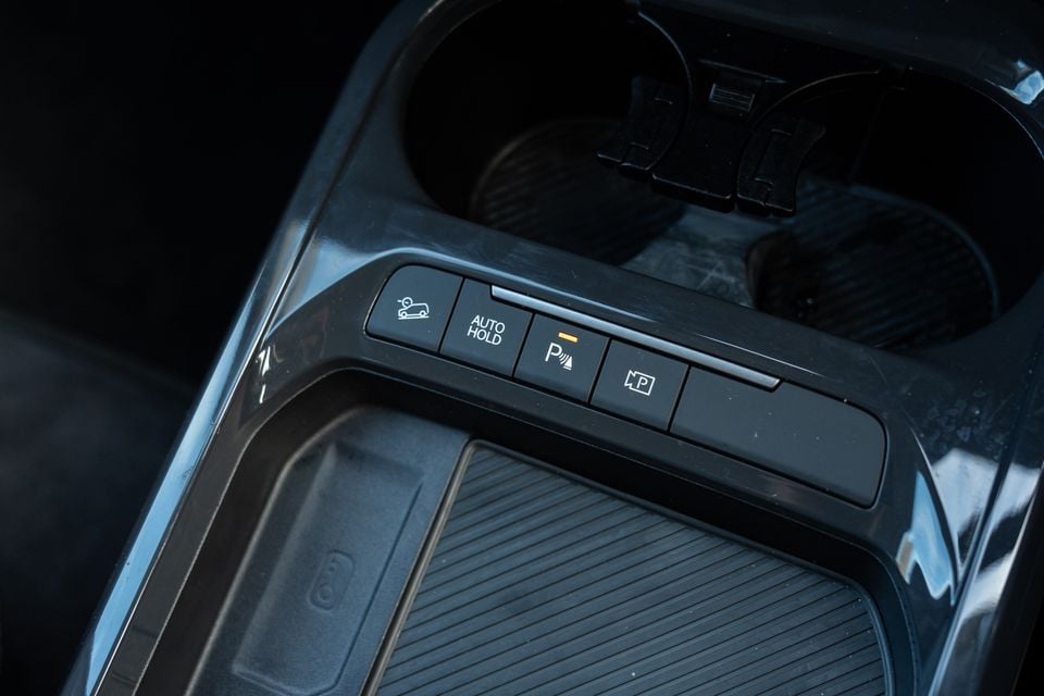 Close-up of the centre console button panel in a Kia EV5, showing controls for traction, auto hold, parking sensors, and auto parking
