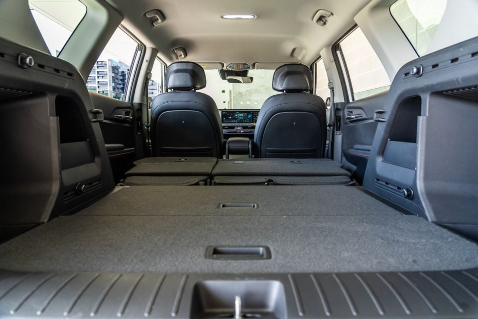 Interior cargo area of a Kia EV5 SUV with rear seats folded flat, showing a large extended boot space viewed from the tailgate