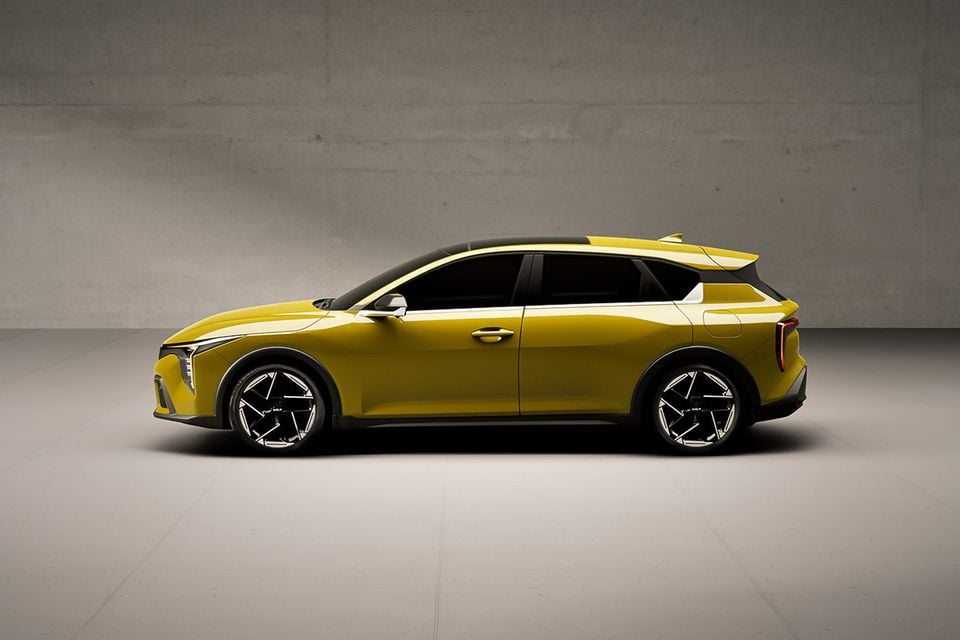A yellow Kia K4 hatch hybrid shown in side profile in a grey studio