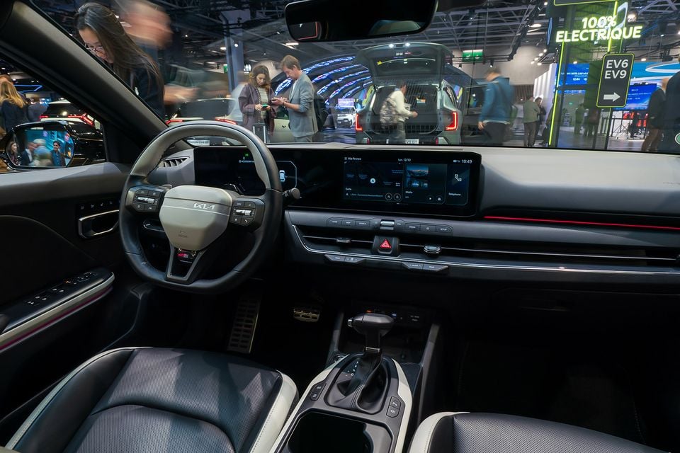 Dashboard and front seats of the Kia K4 hatch hybrid, showing the steering wheel, curved twin screens and gear selector, on display at the Paris Motor Show