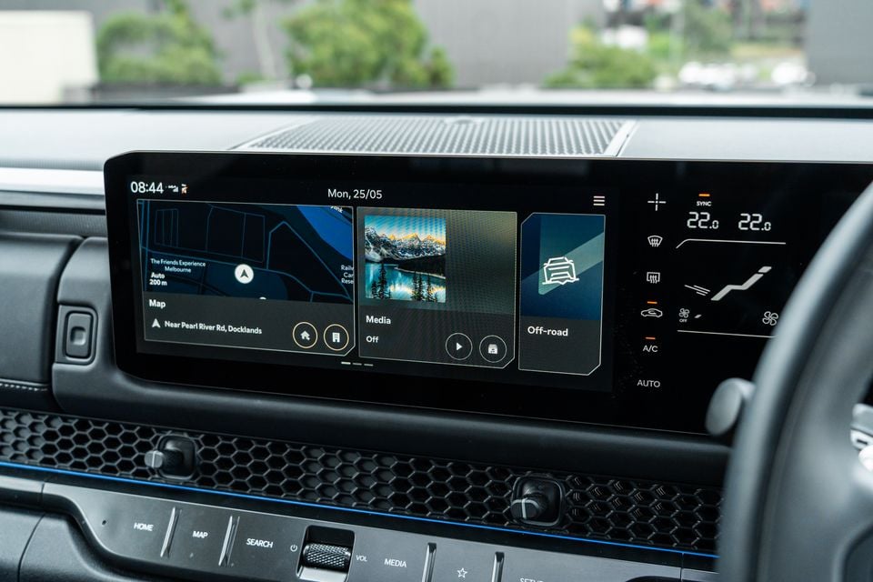 The touchscreen infotainment display and climate controls on the centre console of a Kia Tasman X Pro, showing navigation, media, and off-road widgets