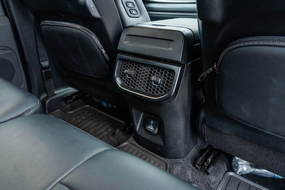 Rear centre console of the Kia Tasman X-Pro showing rear air vents, climate controls, and a 240V AC power outlet between the back seats
