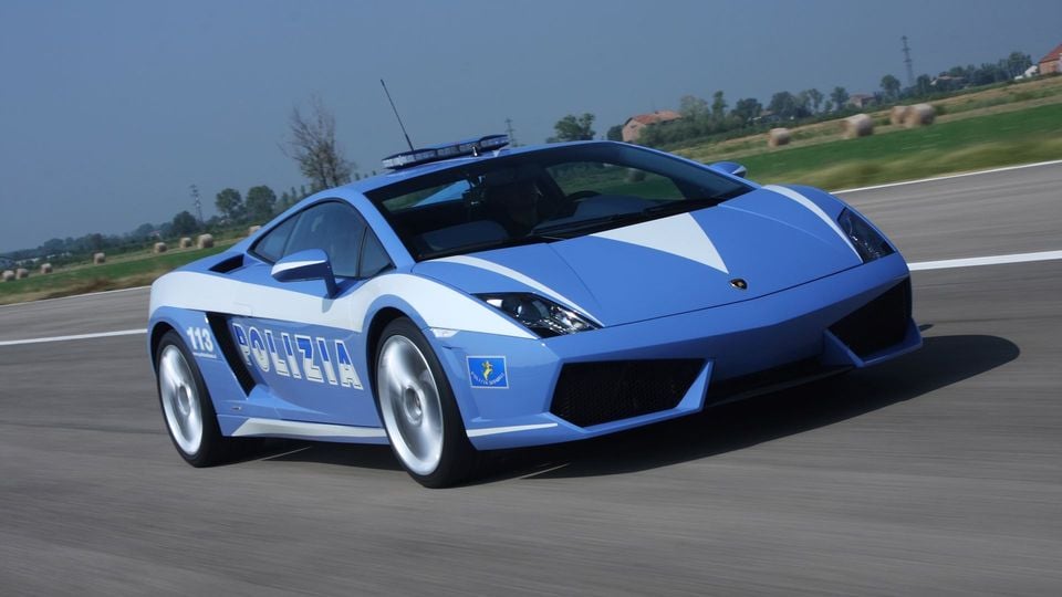 A Lamborghini Gallardo in Italian Polizia livery driving on a road, seen from the front-side