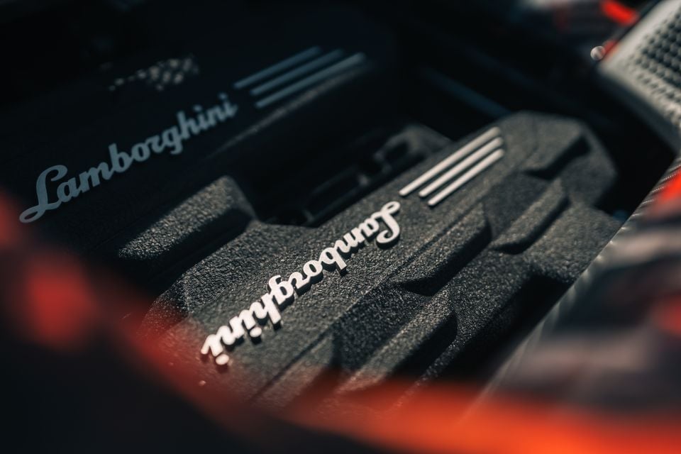 Close-up of a Lamborghini Revuelto SV engine cover showing the Lamborghini script badge and textured engine components