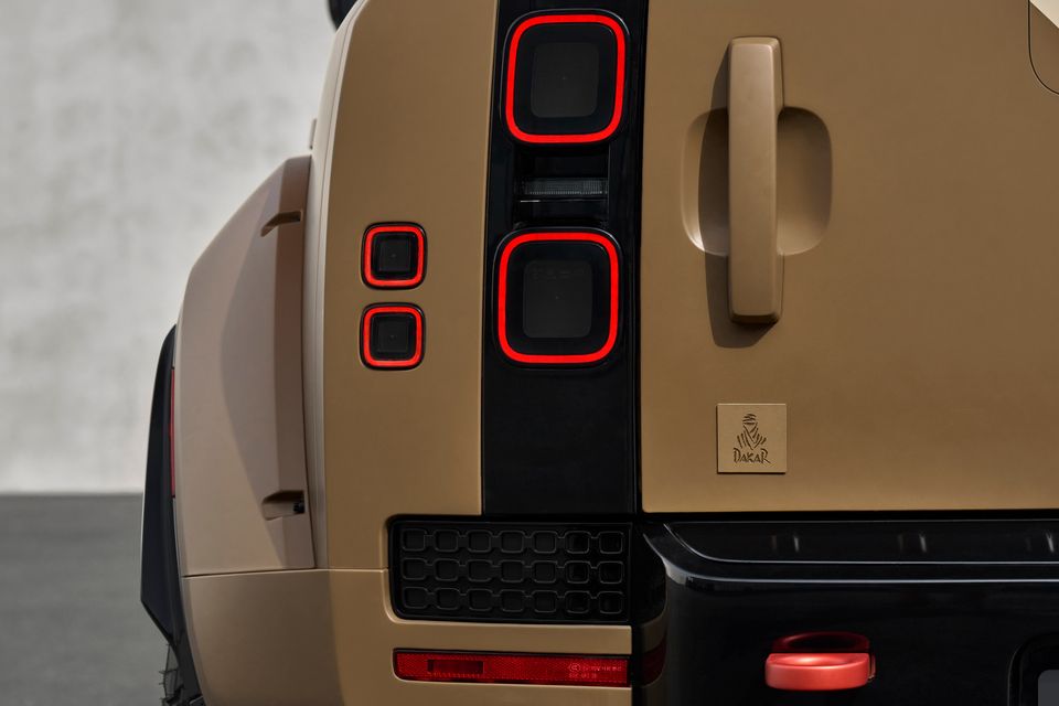 Close-up of the rear tail lights and Dakar badge on a Land Rover Defender Dakar edition in a tan/gold colour